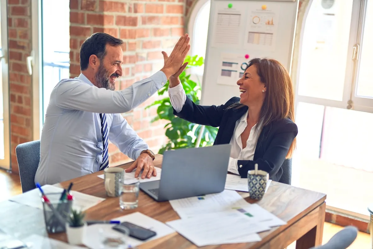 Two business professionals high-fiving in an office